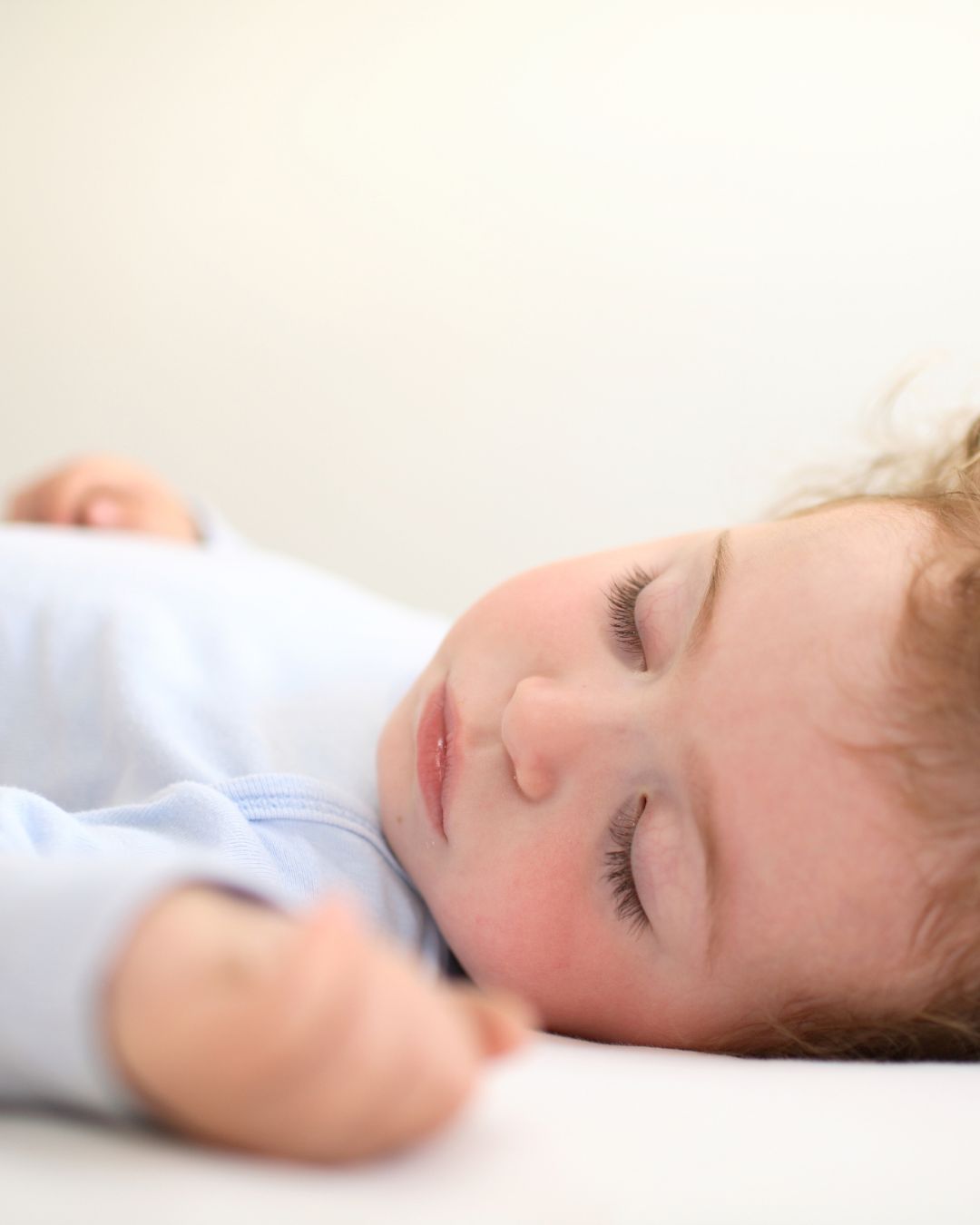 Rustig slapend kindje in een lichtblauwe pyjama, zelf in zijn bedje